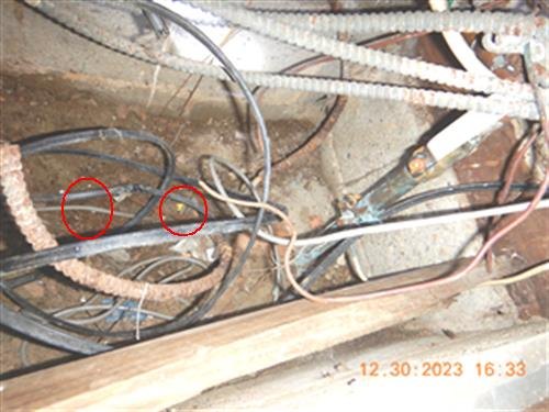 Electrical cables and pipes beneath floor framing with two points circled in red, date stamp