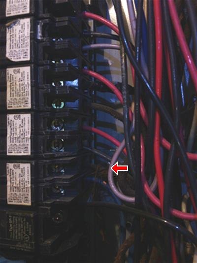 Red arrow among wires beside a column of circuit breakers inside an electrical panel