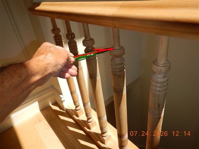 Inspection photograph of a hand testing stair balusters for movement