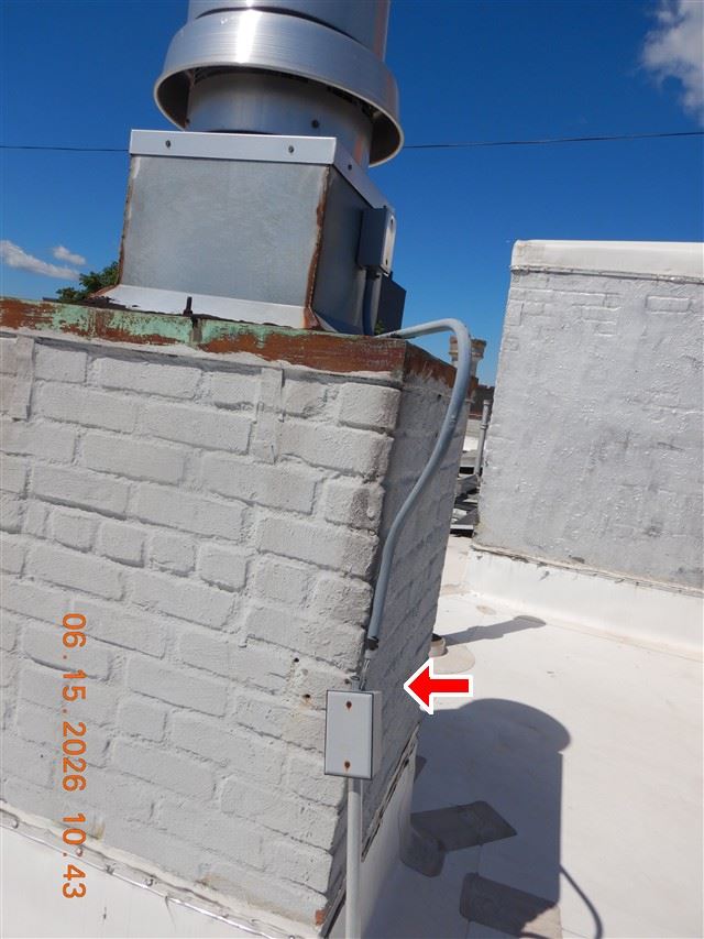 Inspection photograph of a rooftop chimney with a metal flue cap