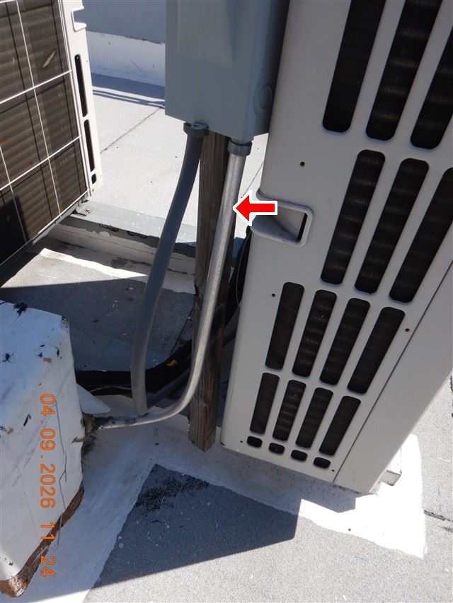 Inspection photograph of an air conditioning condenser on a flat roof with its service disconnect alongside