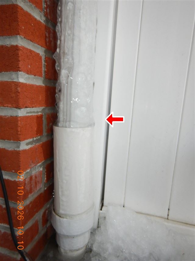 Inspection photograph of a downspout discharging at the base of a masonry wall