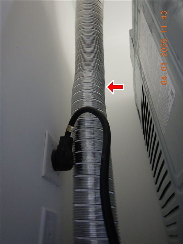 Inspection photograph of a flexible metal dryer exhaust duct with the appliance cord run across it