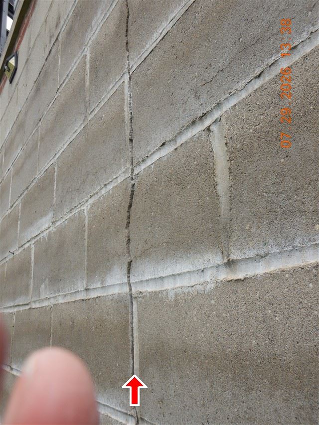 A crack in a block foundation, marked so it can be found and measured again.