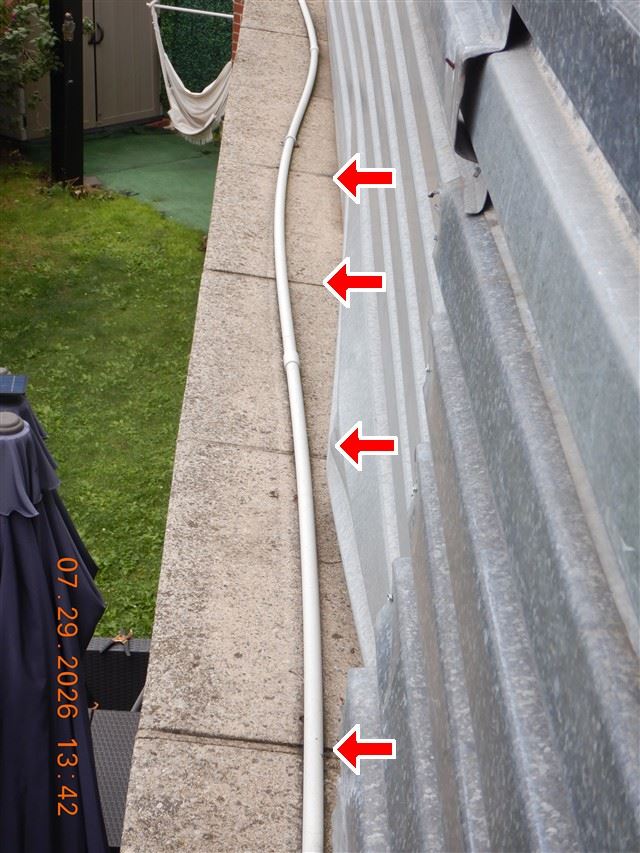 Inspection photograph of a gutter holding leaf debris and standing water, with arrows marking the blocked run