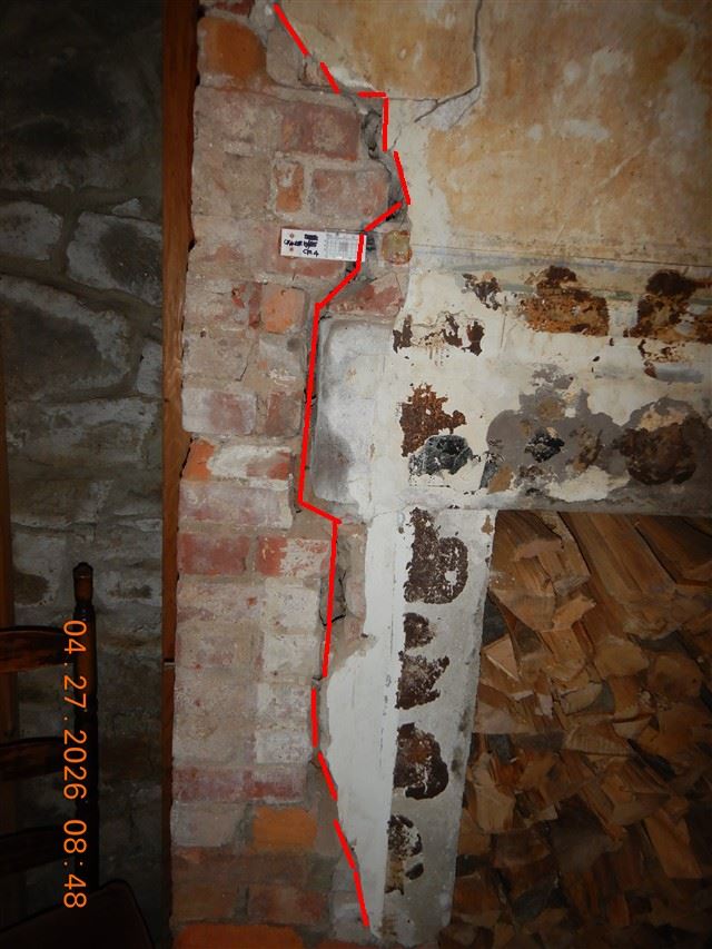 A crack traced through brick and mortar with a numbered gauge fitted across it, so movement can be measured on a return 