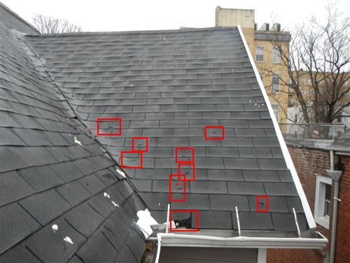 Inspection photograph of a slate roof with individual defects outlined in red across the slope