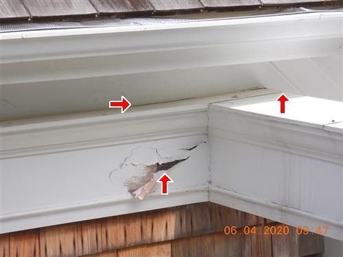 White fascia and soffit at a roof corner with peeling paint and a split in the trim, three red arrows.