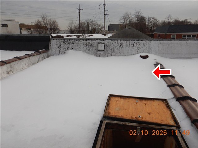 A snow-covered flat roof with an open roof hatch and parapet walls, one arrow marking the roof surface.