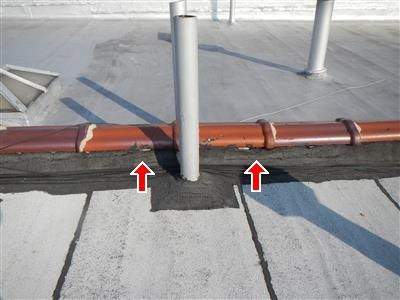Clay coping tiles on a parapet wall with two red arrows at open mortar joints