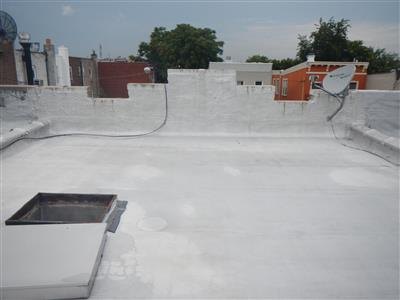 Flat roof with white reflective coating, parapet walls, roof hatch and skylight curb