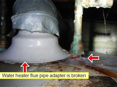 Top of a water heater with a grey flue draft hood and a corroded cold water pipe, with red arrows and a label reading water heater flue pipe adapter is broken.