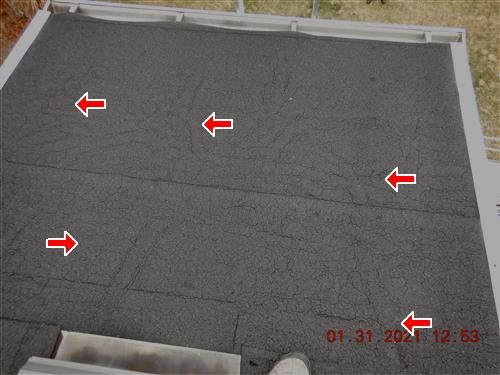 Grey flat roof section between gutters with a web of surface cracks, five red arrows marking the cracking.