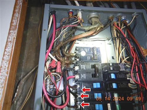 Open electrical panel with breakers and bundled wiring; three red arrows point to frayed cloth-covered conductors on the left side.