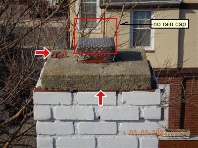 Top of a painted brick chimney with a flue tile, a red box labelled no rain cap and red arrows on the cap.