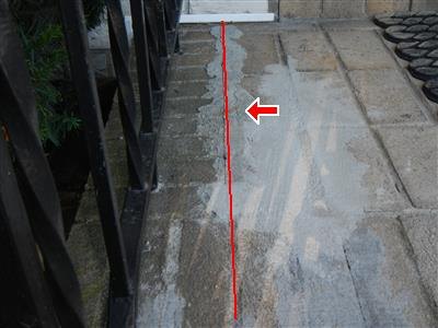 Concrete stoop landing with a red line traced along a patched crack