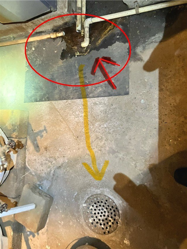 A basement slab floor drain with a leaking pipe joint circled and traced in red above it.