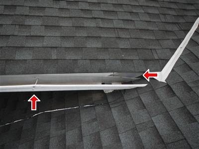 Dark asphalt shingle roof with lifted white metal trim and two red arrows at gaps