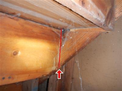 Rough wood framing junction with a red line and arrow tracing a split in a beam