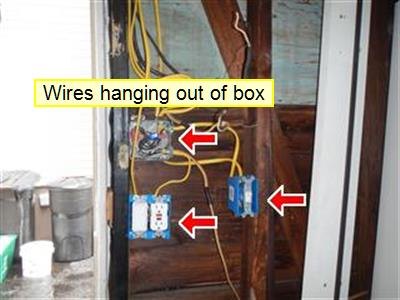 Exposed wall framing with outlets, loose yellow cable, and label reading wires hanging out of box