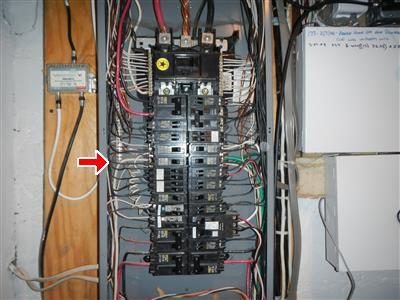Open main electrical panel with a full column of breakers and a red arrow pointing at the left bus.