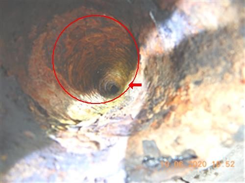 Camera view down the inside of a rusty pipe, with a red circle and arrow marking the clear bore.