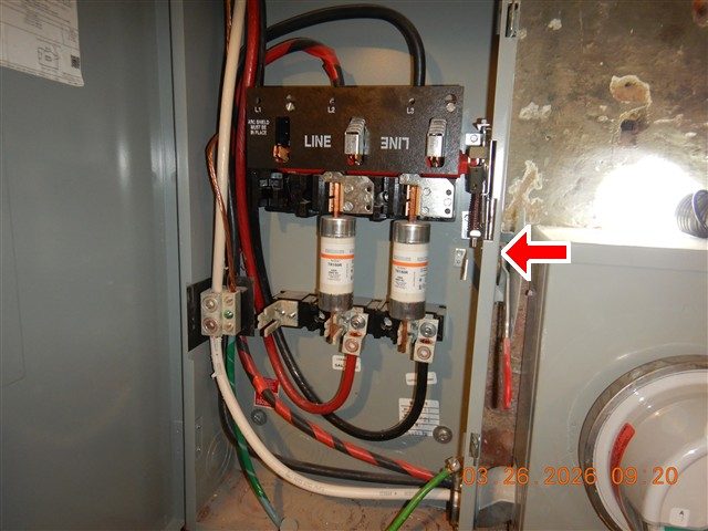 Open grey disconnect box with two cartridge fuses and black and red service cables, a red arrow pointing at the switch linkage on the right side.