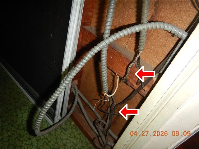 Attic closet framing with armoured cable loops and loose bare wires, two red arrows pointing at the wires.