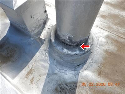 Base of a silver-coated chimney flue pipe on a flat roof with a red arrow pointing at the sealant around it.