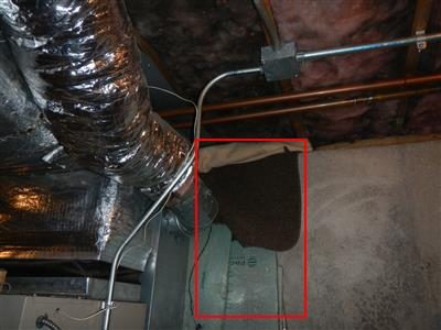 Basement boiler area with a dark mat draped over the fresh air intake, outlined with a red box.