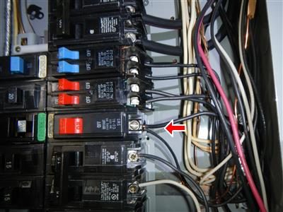 Inside an electrical panel, a red arrow points to two wires under one breaker terminal.