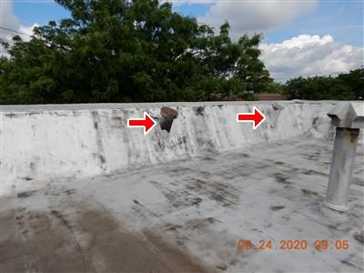 White-coated flat roof with a parapet wall; two red arrows mark vents in the gable section behind it.