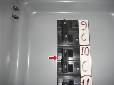 Circuit breakers in an electrical panel with handwritten circuit labels, red arrow at one breaker.