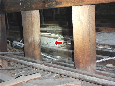 Crawlspace with wood posts, armored cable runs, and a red arrow at a junction box.