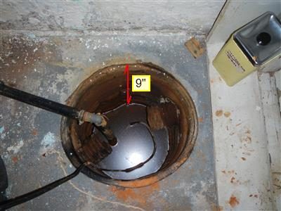 Sump pit in a concrete floor filled with water, with a red arrow labelled 9 inches showing the water level.