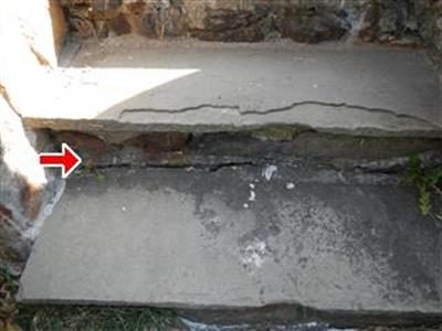 Two wide stone steps with open, crumbling cement joints between them, red arrow at the joint.