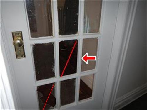 An original white-painted glass-panelled interior door with one cracked pane traced in red.
