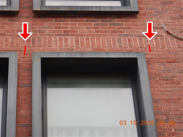 A newer red-brick facade with hairline cracks above the window lintels marked by red arrows.