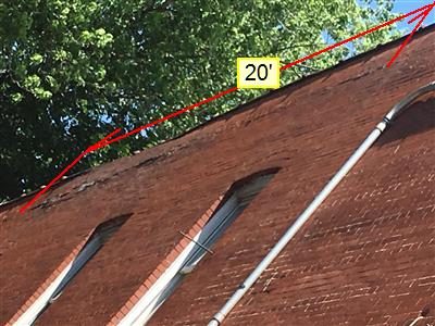 Brick side wall of a building seen from below with a red line and 20 foot label marking the deteriorated parapet.