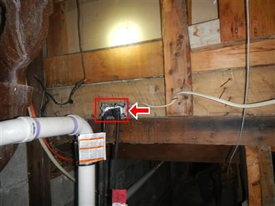 Basement framing with a red box and arrow around a junction box with wires hanging out next to a PVC pipe.