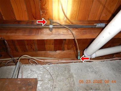 Red arrows at two fittings on copper tubing running along basement ceiling framing, date stamp visible