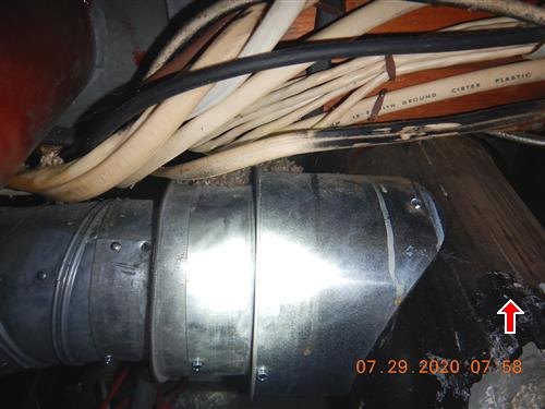 Bundle of old cloth-sheathed wiring draped over a metal duct in a dark attic space