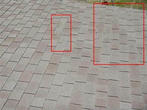 Asphalt shingle roof with two red boxes outlining areas where shingle tabs are missing.