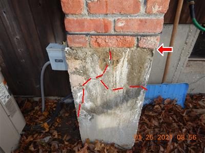 Concrete chimney foundation below brick with red dashed lines tracing cracks, red arrow at the top.