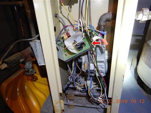 Boiler burner compartment with a circuit board and loose wiring, a red arrow pointing at the control box.