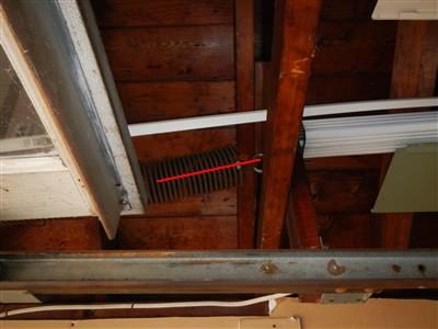 Garage ceiling framing with a red line along a lift spring beside the door track.