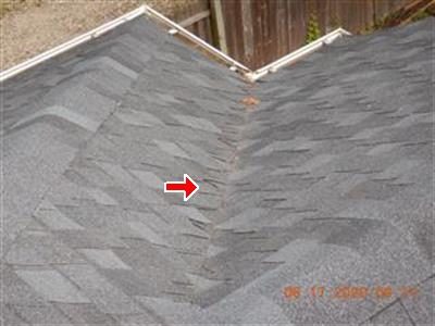 Roof valley on a new asphalt shingle roof with a red arrow at the valley centre.