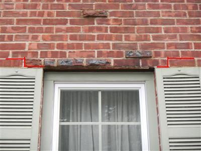 Brick wall above a window with shutters, red lines marking a rusted steel lintel pushing the brick courses up.