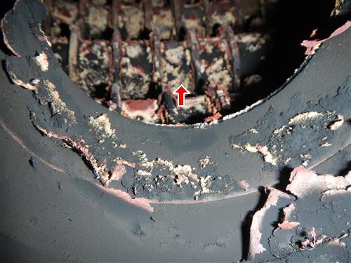The inside of a boiler combustion chamber with its lining deteriorating, marked with a red arrow.