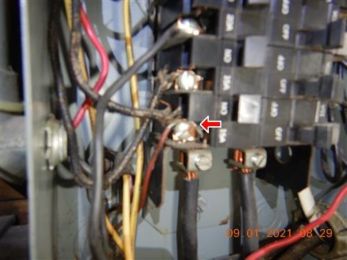 A close view inside an electrical panel showing older conductors and lugs, one connection arrowed.